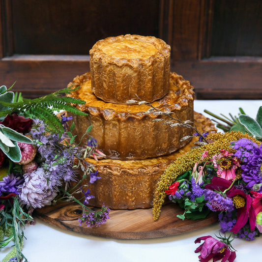 Three-tiered wedding cake with floral decorations on a wooden board.