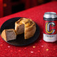 Love Heart pork pie with a slice removed on a black plate next to a can of Frisby beer on a red table cloth with hearts.
